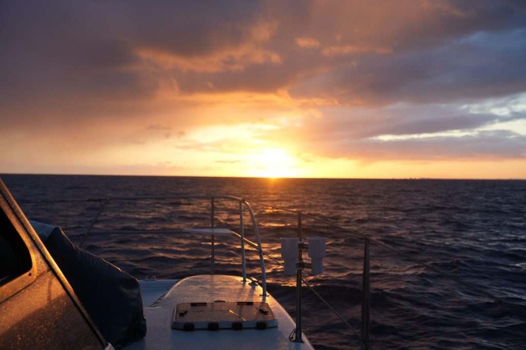 Sunset over calm ocean viewed from boat deck in Hawaii.