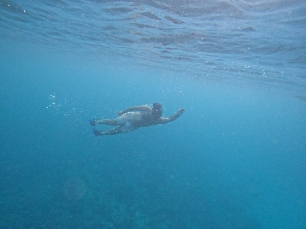 A man enjoying the best snorkeling Oahu has to offer in vibrant, clear blue waters with tropical fish.