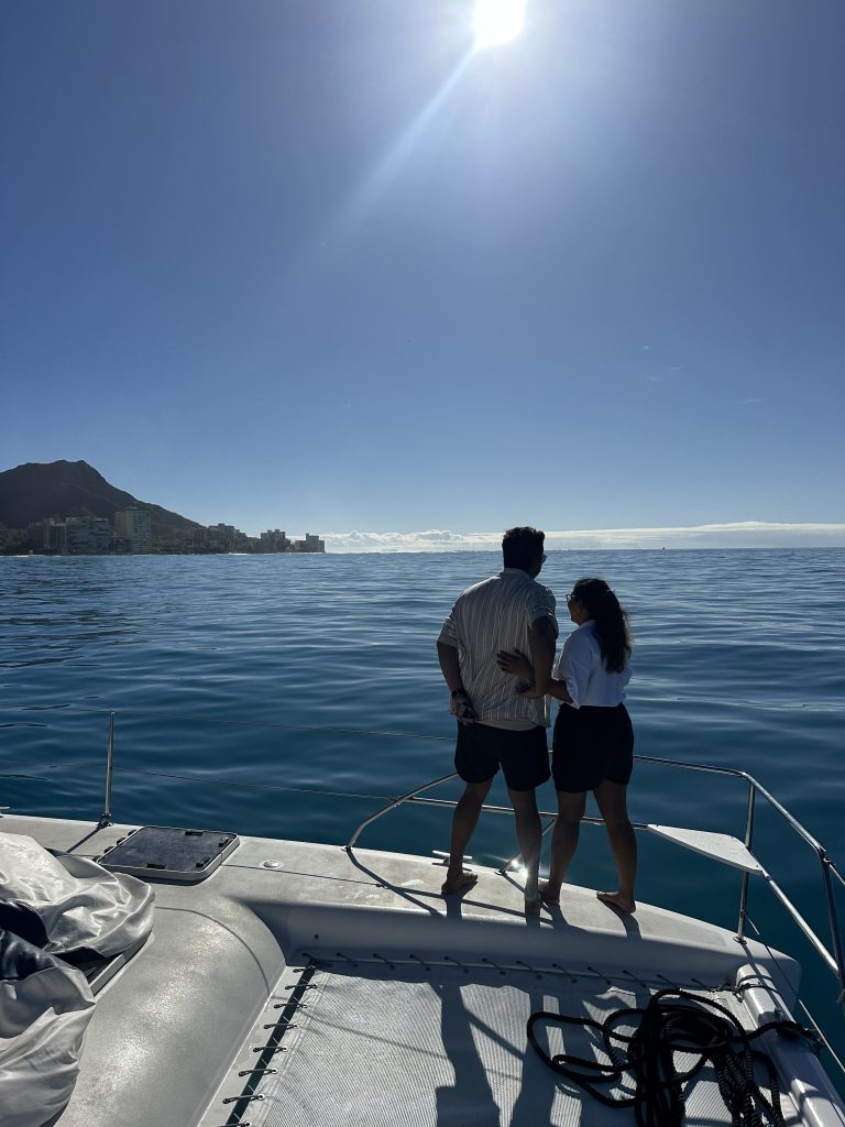 Couple enjoying the beautiful Hawaii ocean views by standing on the deck of a boat. 