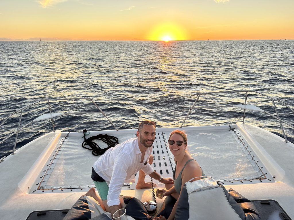 Couple relaxing on the deck of a private catamaran during a stunning Honolulu sunset cruise, enjoying a romantic boat experience.