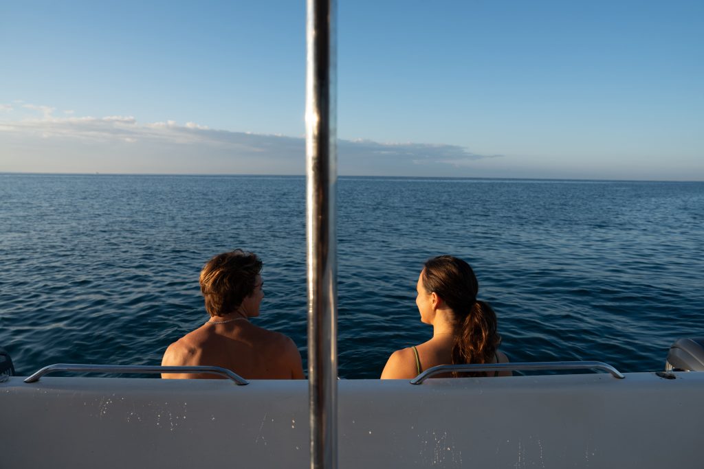 Couple relaxing on a Hawaii boat charter while looking out at the ocean.