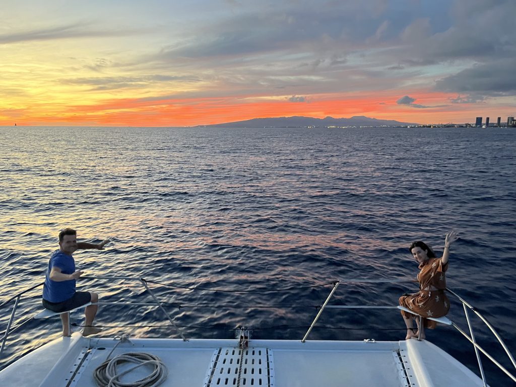 Couple enjoying a Hawaii sunset cruise on a private boat with ocean and island views.