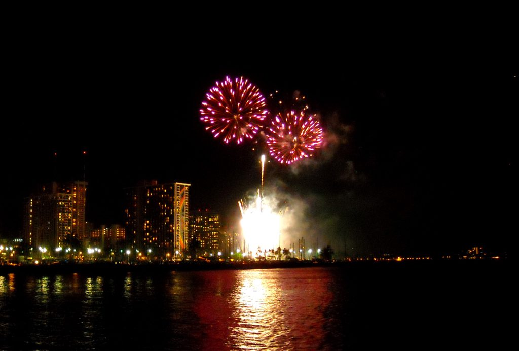 Fireworks over the Hawaii skyline reflected on the ocean.
