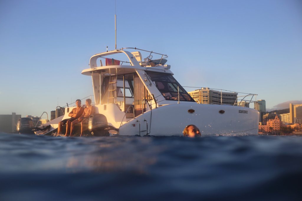 Guests relaxing beside catamaran near Waikiki at sunset