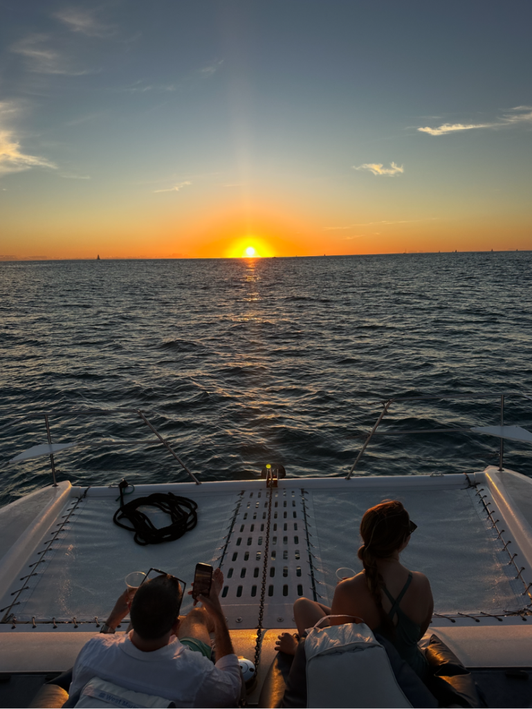 Couple watching a golden sunset from a catamaran