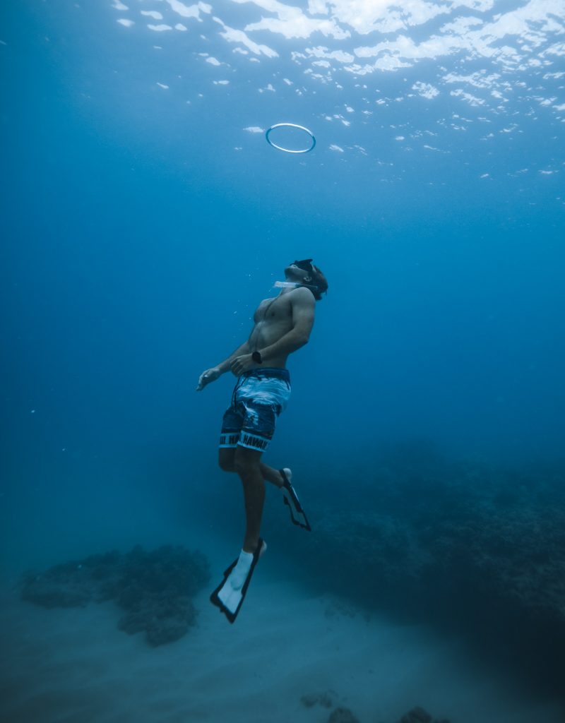 Freediver ascending toward surface with bubble ring
