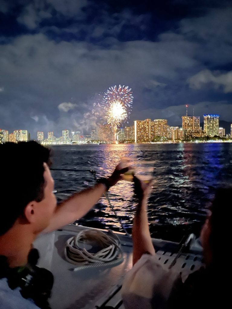 Guests toasting drinks as fireworks light skyline