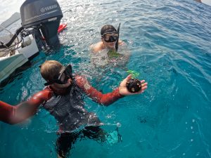 Snorkelers holding sea urchin near boat motor