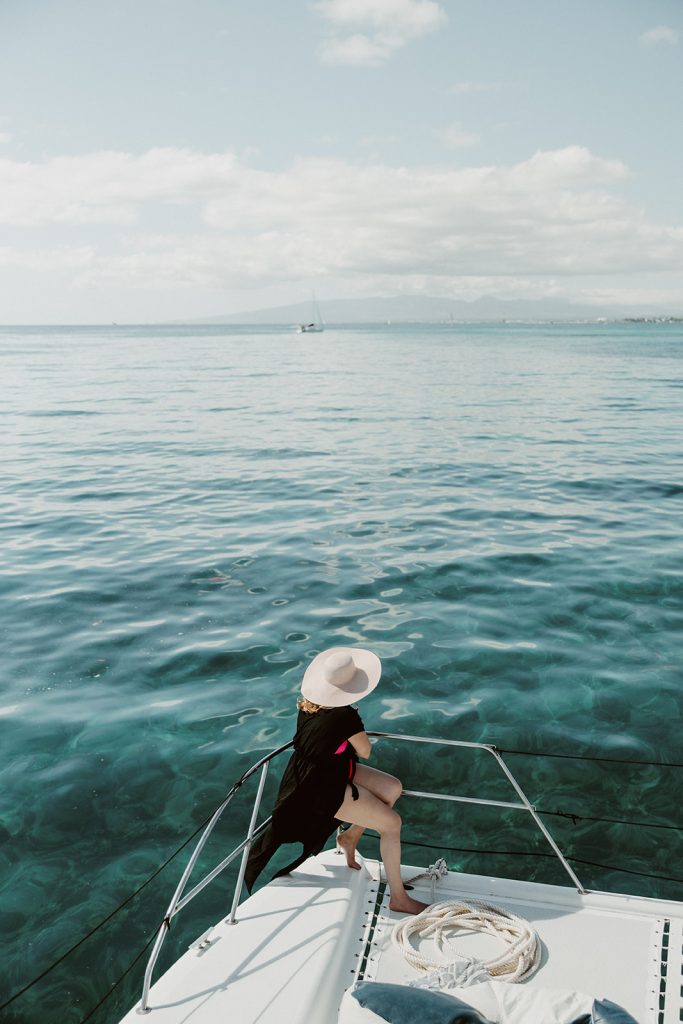 Woman in sun hat sitting on catamaran bow