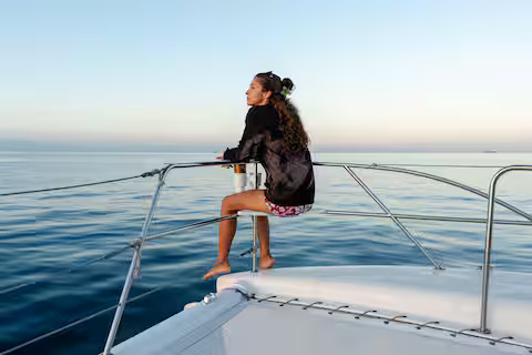 Woman relaxing on catamaran netting over ocean