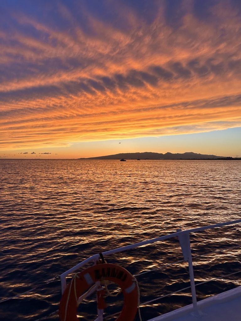 Boat railing view of fiery sunset clouds
