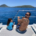 Father and daughter on catamaran near mountains