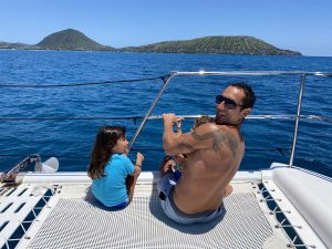 Father and daughter on catamaran near mountains