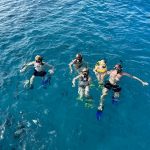 Guests enjoying a guided snorkeling experience in Waikiki, Hawaii, with snorkeling gear and flotation support.